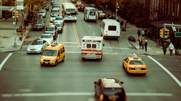 A city street with an ambulance, buses, cars, and taxis