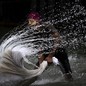 A person splashes water while washing clothes in a river.
