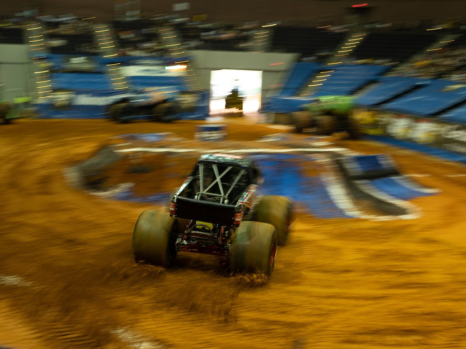 A monster truck is spinning tires in the arena.