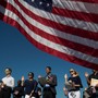 Framed by an American flag, immigrants raise their right hands and take the oath of allegiance during a naturalization ceremony.