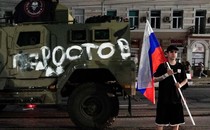Photograph of a man holding aRussian flag next to an army tank