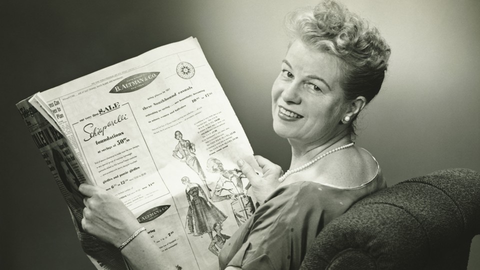 A black-and-white image of a woman reading a 1950s newspaper
