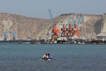 Boys sit on a piece of styrofoam sheet as they search for crabs in front of the Gwadar port in Pakistan.