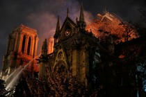 Sparks fill the air as Paris fire-brigade members spray water to extinguish flames as Notre-Dame Cathedral burns.