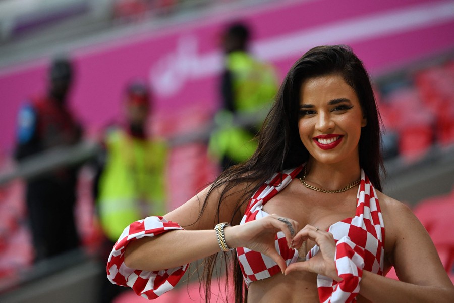 A soccer fan poses for a photo, making a heart with her hands.
