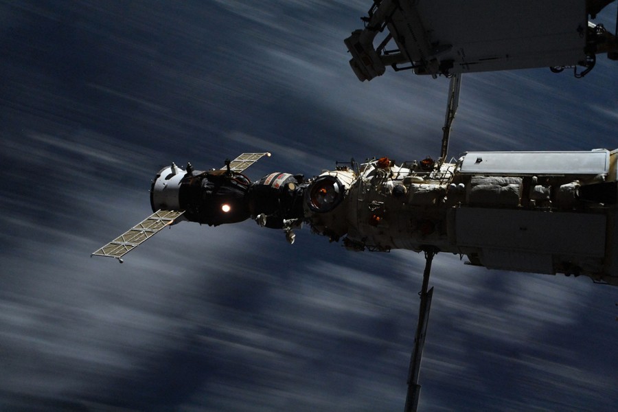 A spacecraft docks with the International Space Station, with clouds seen moving past below.