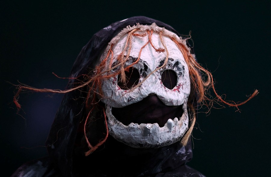 A person wears a frightening skull-like mask and hood.