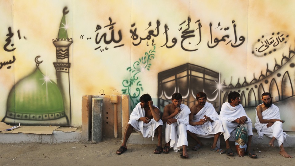 Muslim pilgrims rest in front of a mural depicting the Kaaba in the Grand Mosque during the haj pilgrimage.