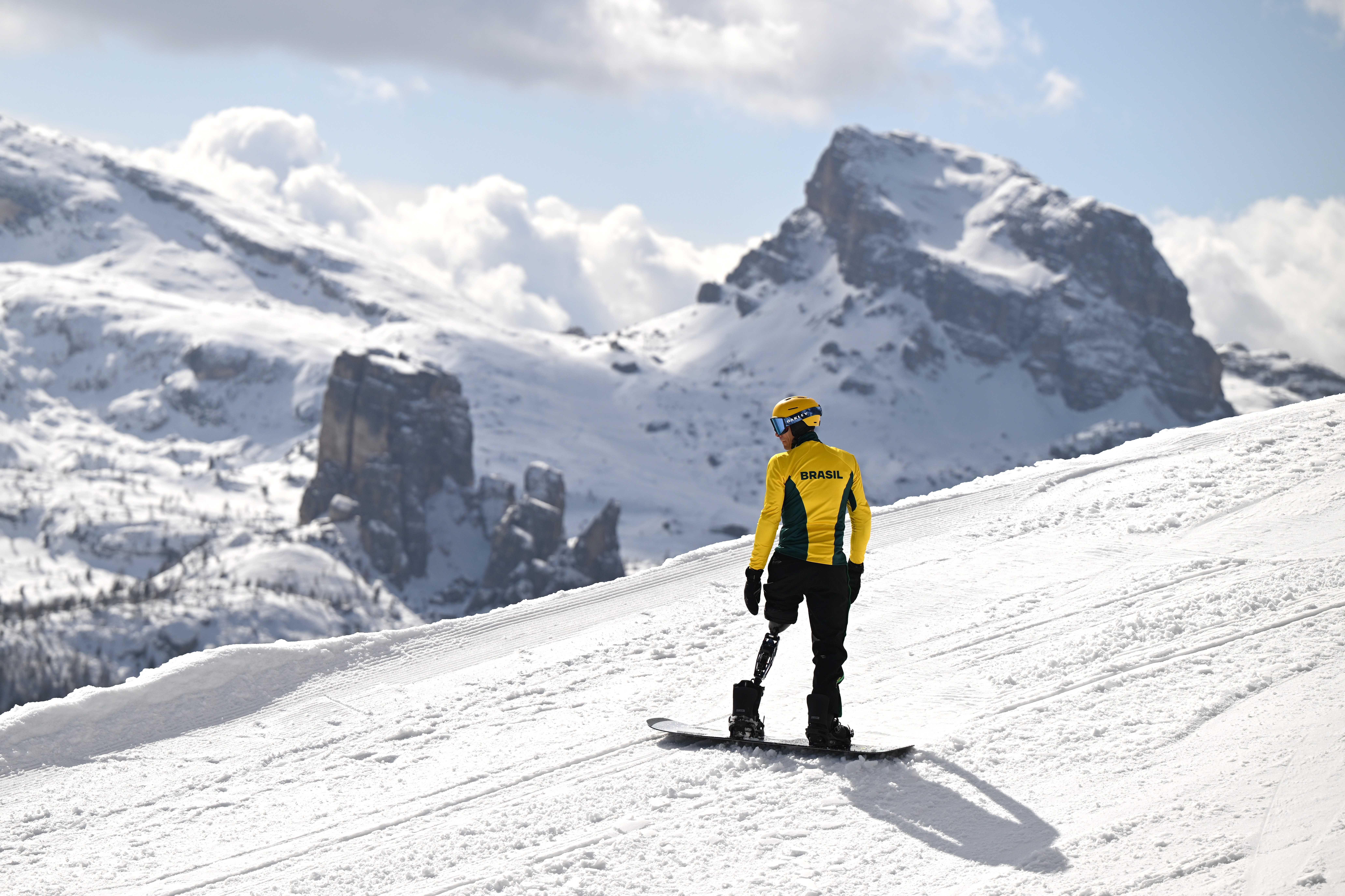 A snowboarder with one prosthetic leg trains on a snowy mountainside.