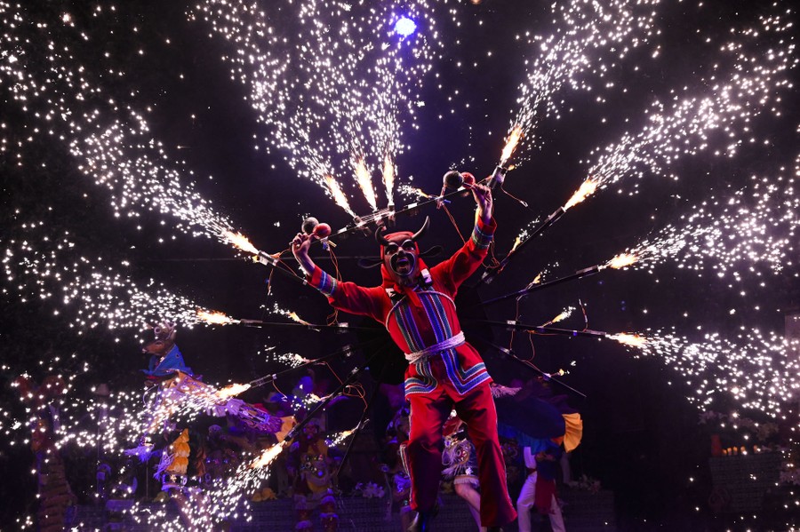A performer dances in a rig that shoots sparks out in many directions.