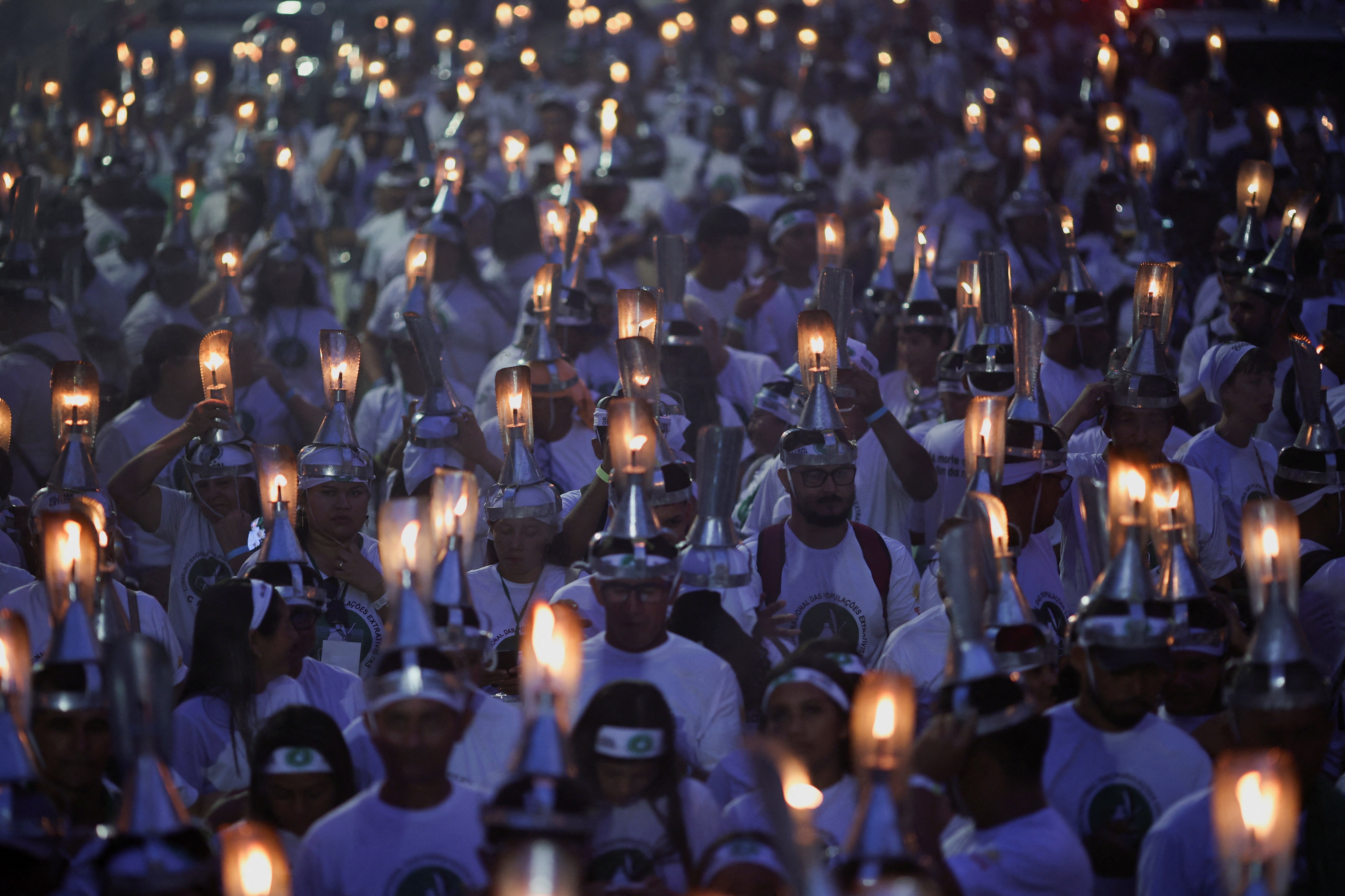 Protesters march while wearing lit oil lamps on their head.
