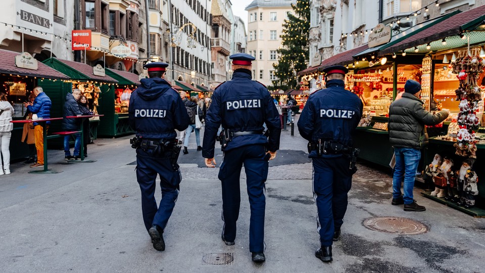 Three police officers patrol through a Christmas market to monitor compliance with the lockdown.