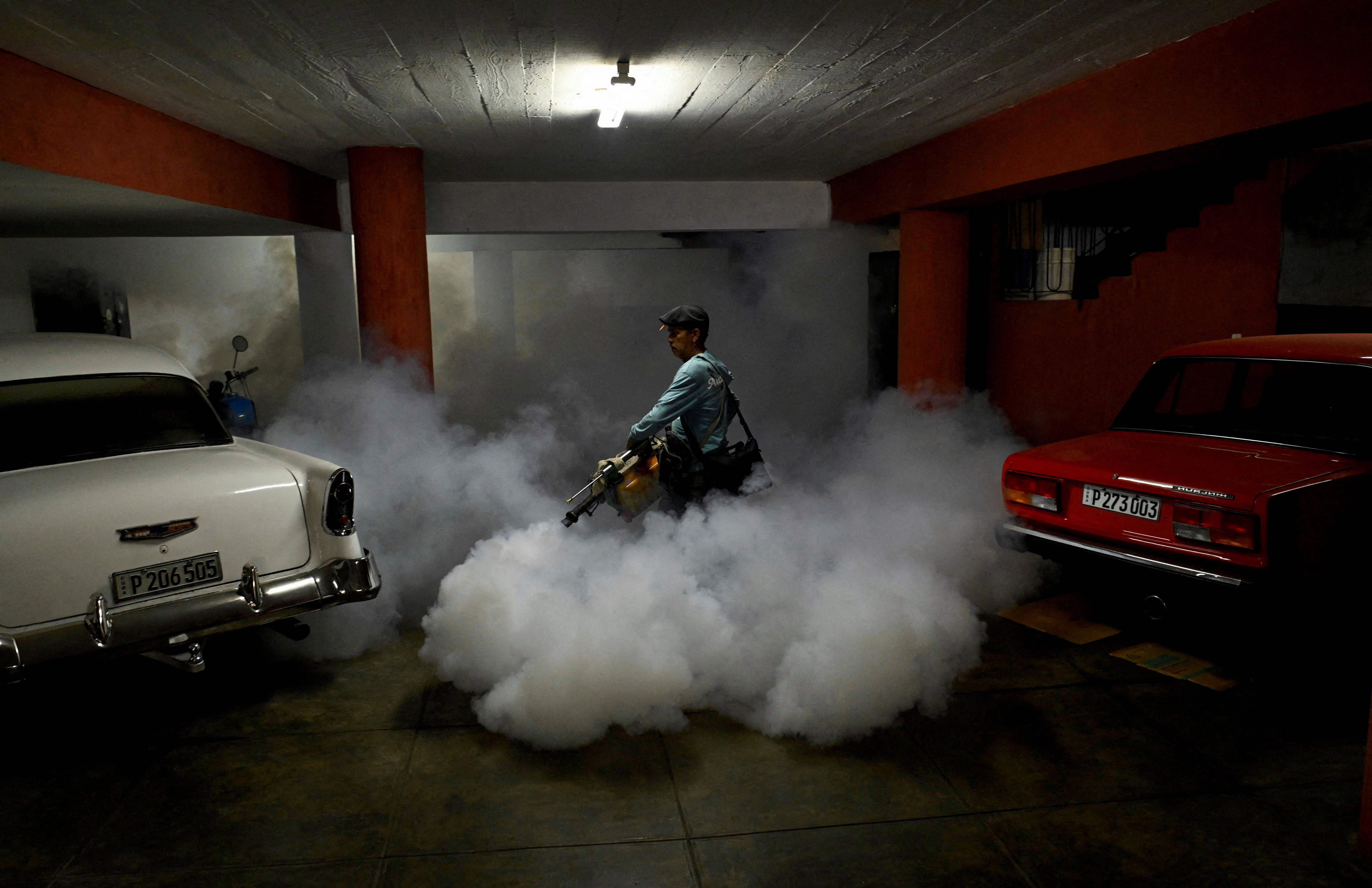 A worker uses a machine to spray pesticide inside a parking garage.