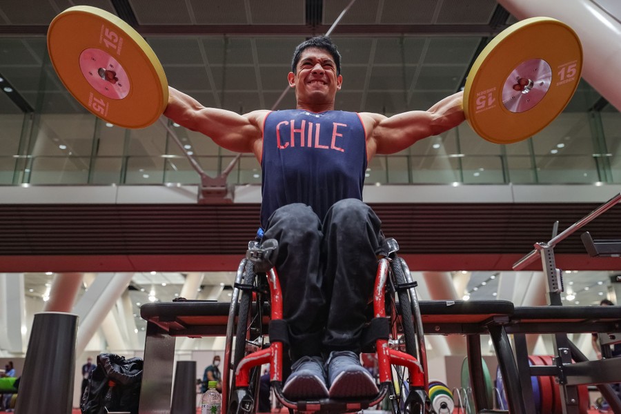 A weightlifter in a wheelchair trains in a gym.