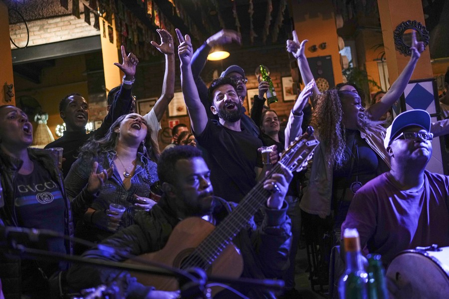 A small crowd sings and celebrates as musicians play.