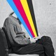 Illustration of seated person reading with a burst of a four-color spectrum coming out of the open book on their lap.