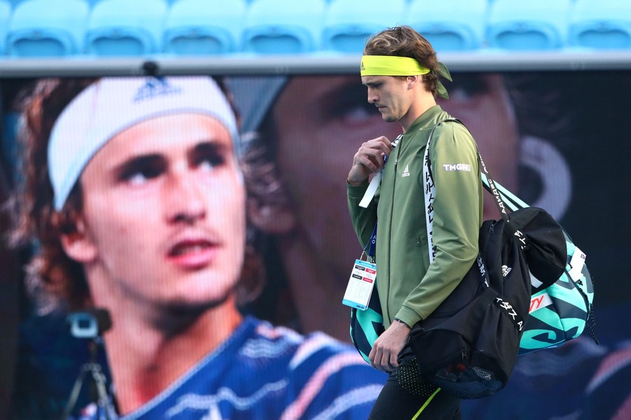 Alexander Zverev walks onto a court in front of a large video screen.