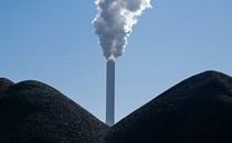 A smoking smokestack stands behind piles of coal at the coal-fired Onyx Kraftwerk Farge power plant.