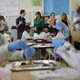 Melania Trump, Queen Rania, and Betsy Devos stand at the back of classroom while black students wearing goggles work on a science experiment.