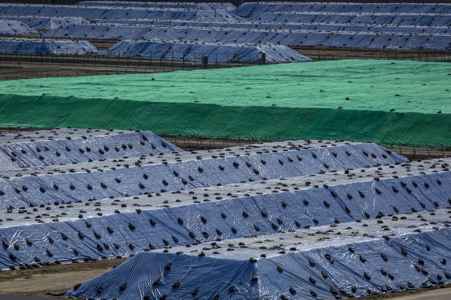 Huge piles of soil sit covered in fabric.