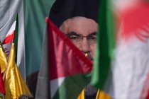 Iranian worshippers wave a Palestinian flag and an Iranian flag in front of a portrait of the Hezbollah leader Hassan Nasrallah.