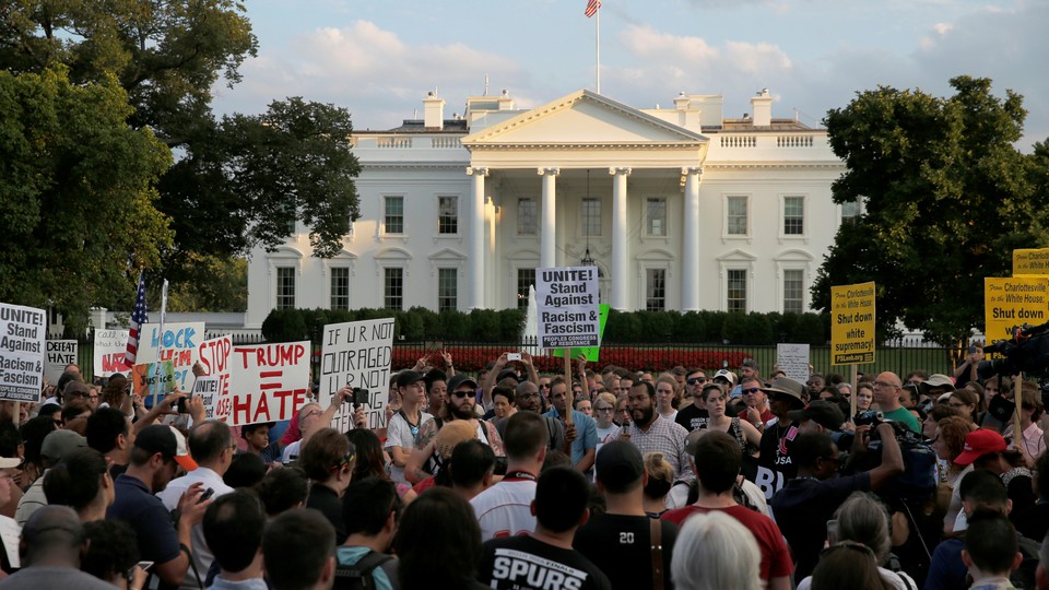People gather with signs outside the White House.