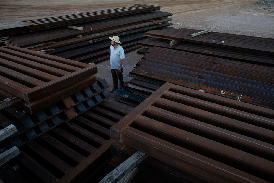 Myles Traphagen, Borderlands Program Coordinator at Wildlands Network, next to a pile of steel bollards left at a border wall construction site at the Guadalupe Canyon, Arizona.  (Photograph by Adriana Zehbrauskas for The Atlantic)