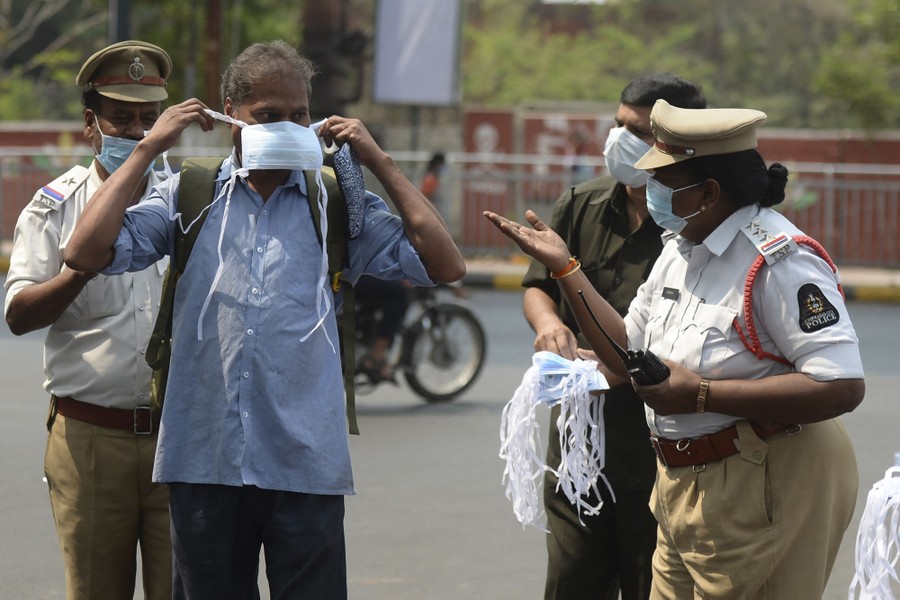 A police officer gestures to a man in a street, who is being offered a mask.