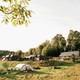 A view of the compound of structures from the southeast, including the big house, the little house, hoop house, garden, windmill, and barn.