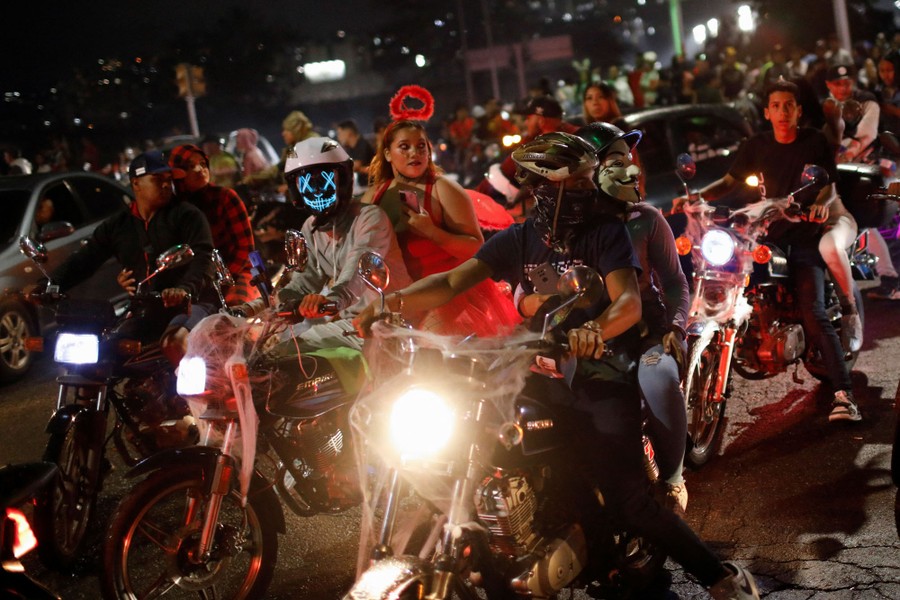 People in costumes ride motorcycles in a group.
