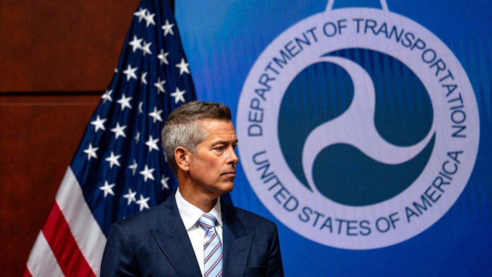 Sean Duffy stands in front of an American flag and a Department of Transportation logo