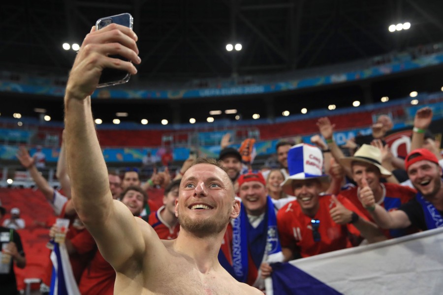 A soccer player takes a selfie with excited fans.