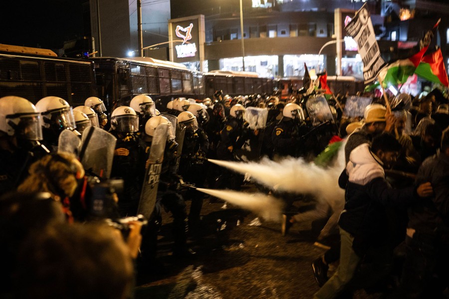 Riot police officers fire tear gas at protesters.