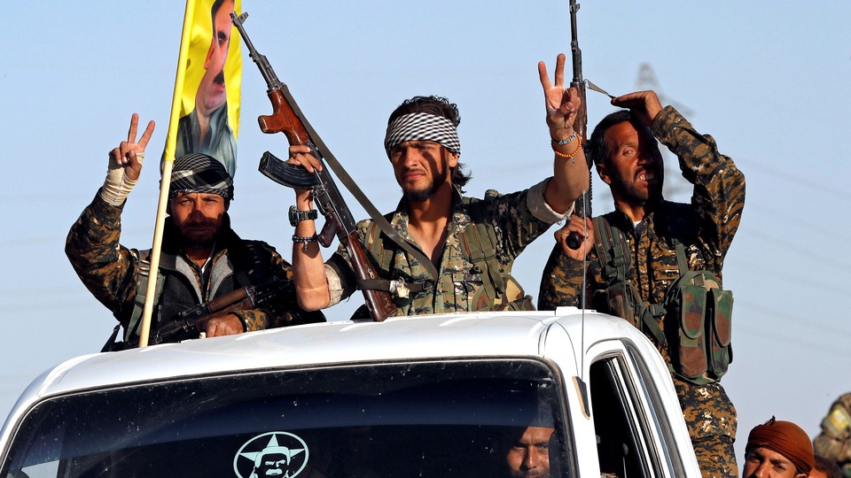 Three fighters of the Syrian Democratic Forces make the V-sign as their convoy passes 