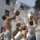 Fraternity brothers throw water at each other using buckets.