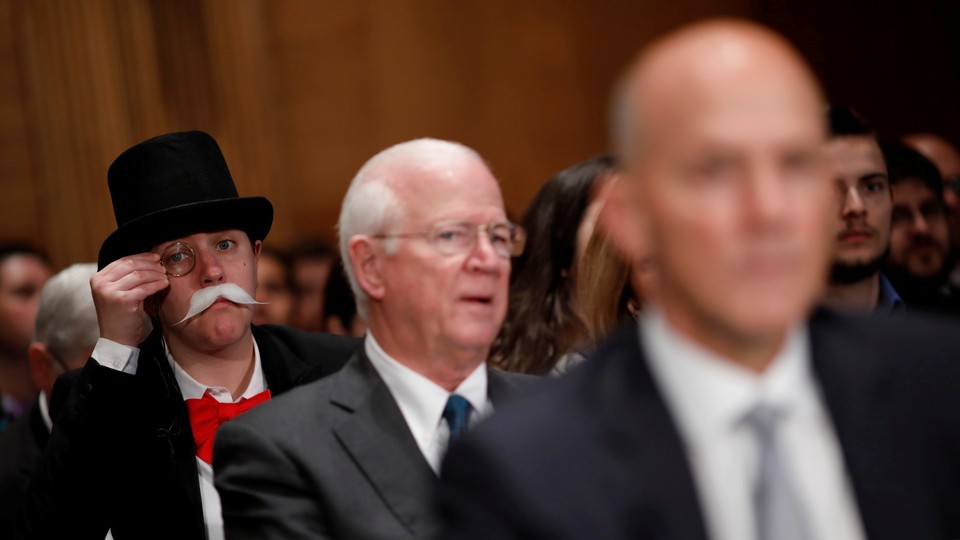 A monocle-wearing spectator looks on as Richard Smith, the former chairman and CEO of Equifax, testifies before the U.S. Senate Banking Committee.
