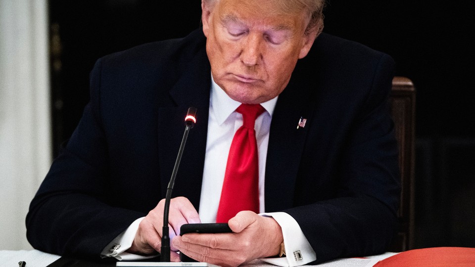 A photograph of Donald Trump using a smartphone.