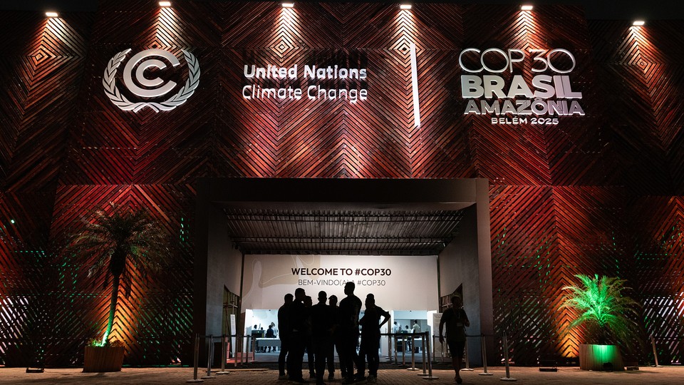 a group of people are silhouetted by the light at the entrance of a pavilion at COP30 in Brasil