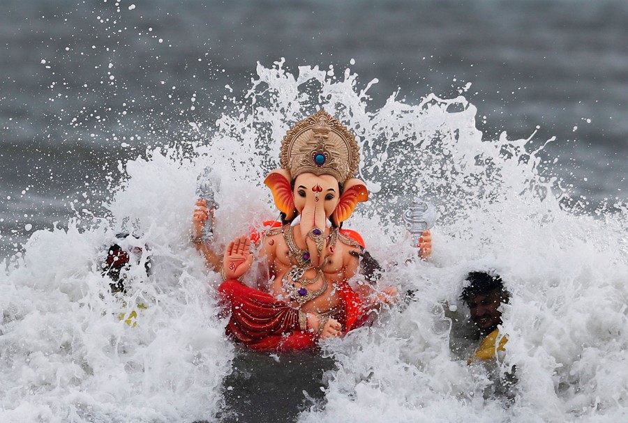 Worshippers carry a statue of the Hindu god Ganesh into the surf.