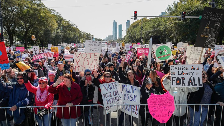 People hold signs during a rally and march at Grant Park on October 13, 2018, in Chicago, Illinois to inspire voter turnout ahead of midterm polls in the United States