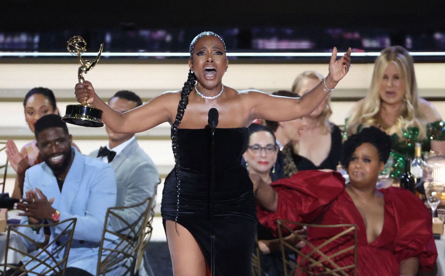 A performer sings while accepting an award onstage.