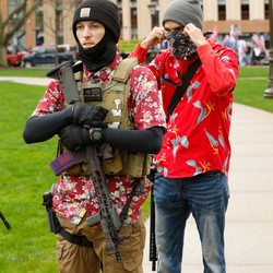 A photograph shows three men standing together—two carry firearms, and two are wearing floral shirts.