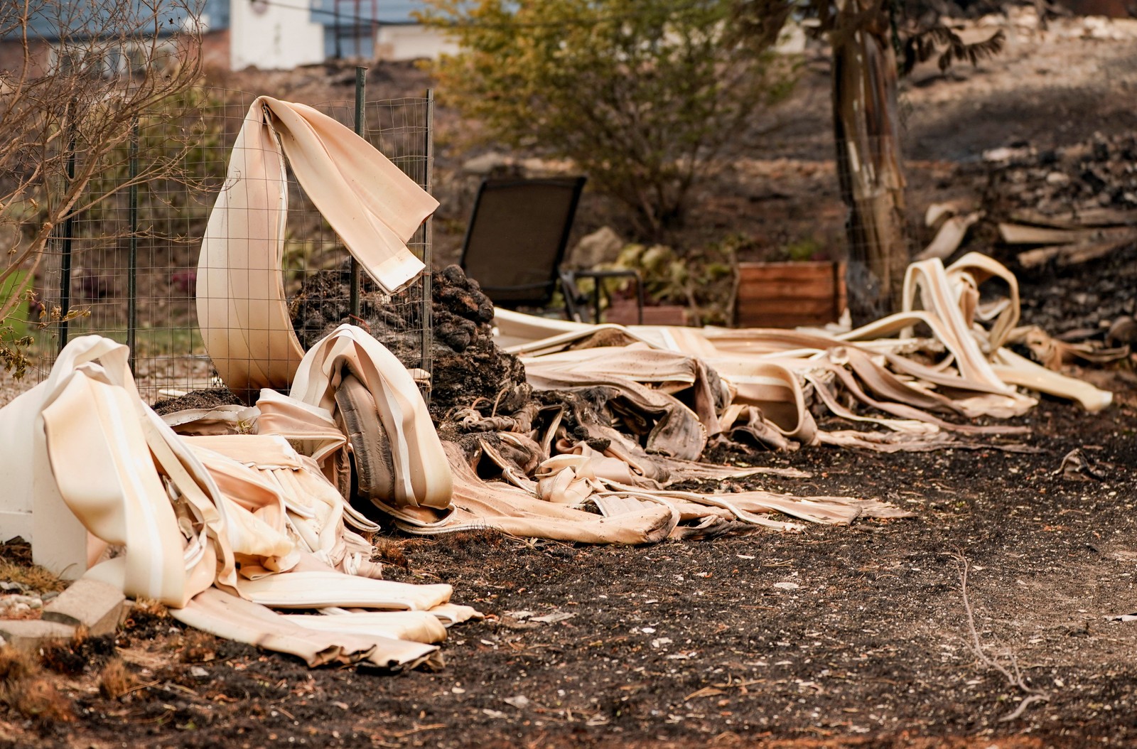 Melted siding lies outside a property damaged by a wildfire.