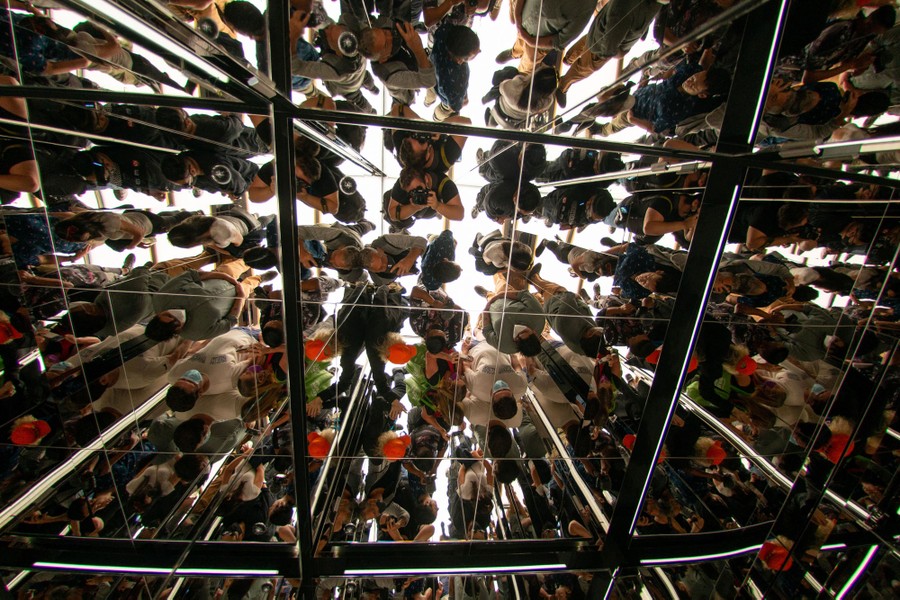 A view looking up inside a mirror-walled elevator full of people