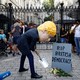 A man wearing a Boris Johnson mask stands outside Downing Street, pretending to dig a grave for "British Democracy."