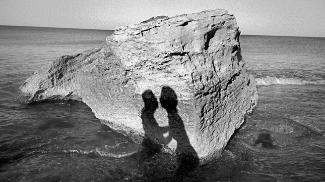 Kissers' reflection on a rock in the ocean