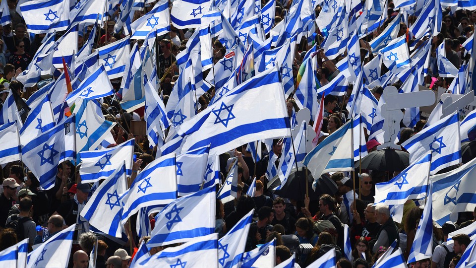 A crowd of protesters waving hundreds of Israeli flags.