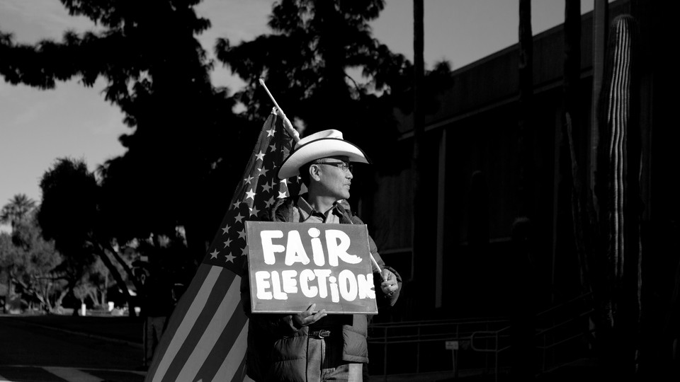 A man holding an American flag and a sign that says "Fair Election"