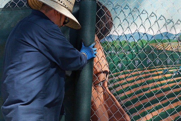 A man covers up a mural of Cesar Chavez