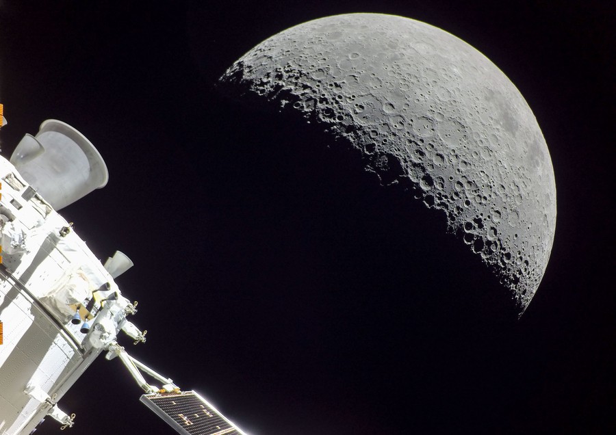 A view of a half-lit moon, seen in space by a small spacecraft